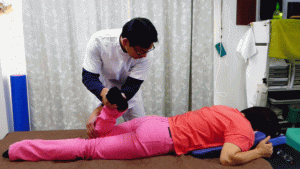 06腰痛整体膝を外から脇につける様に上げて股関節周囲筋を緩める