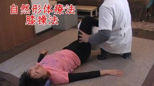 足を伸ばし切ったら、膝周辺の筋肉特に大腿四頭筋を緩めます。画像は自然形体療法という整体術の一種で、太ももの前を緩めながら膝を曲げ伸ばししていきます。