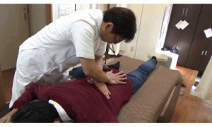 腰椎と仙骨に手掌を押し当てて引き離す様にして椎間関節を牽引していきます