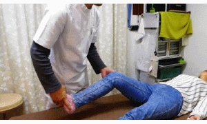 膝を胸につけることで股関節の詰まりをみるその後膝を外側に開いて内もものツッパリをチェック